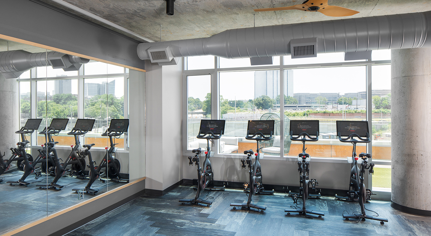 Peace Raleigh Apartments fitness center with large windows and pelotons