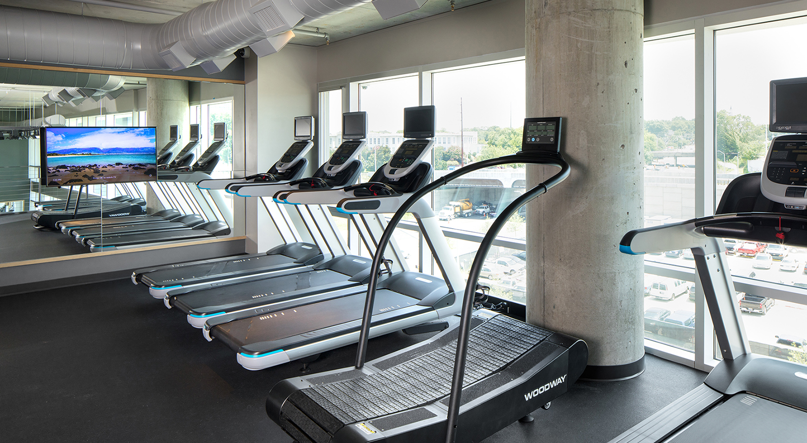 Peace Raleigh Apartments fitness center with large windows and many treadmills