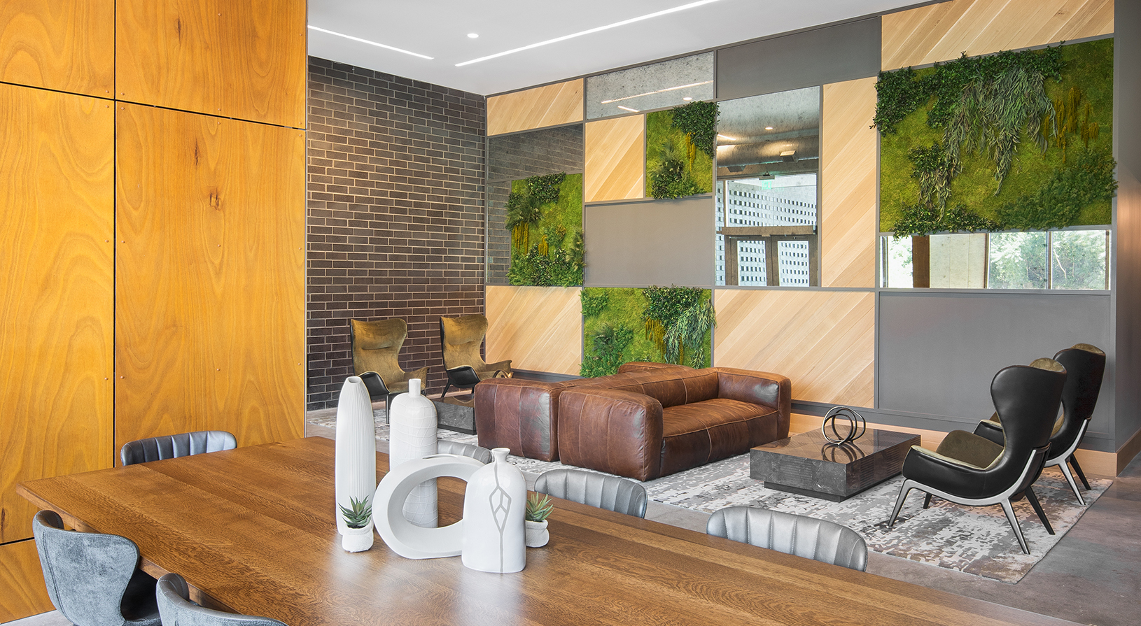 Peace Raleigh Apartments resident lobby with greenery on the walls, a large desk, and multiple seating options