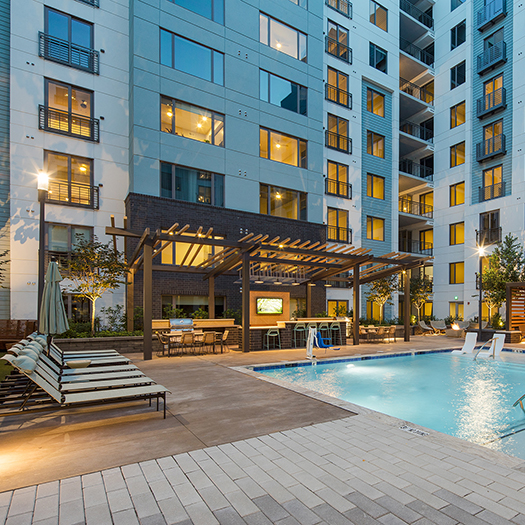 Peace Raleigh Apartments pool, lounge chairs, and grill area for residents at sundown